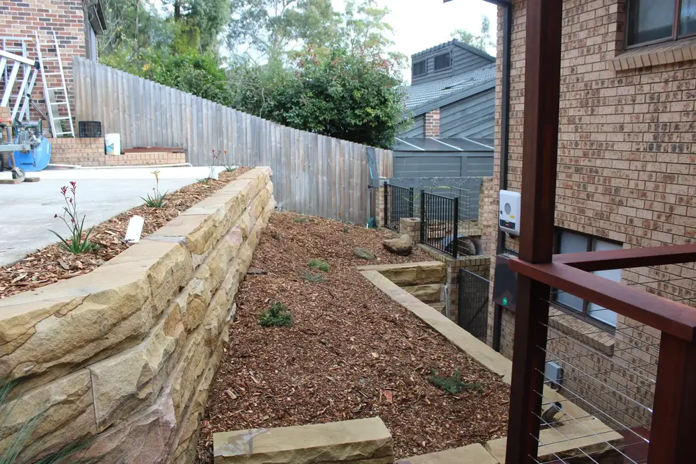 Upper sandstone block retaining wall below the driveway in a Blaxland front yard