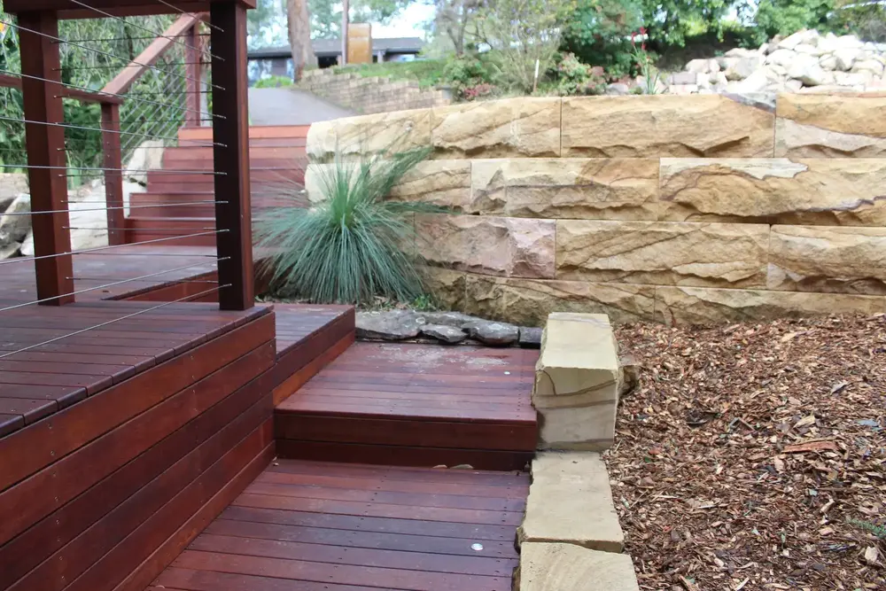 Native planting beside a sandstone block retaining wall and timber steps in Blaxland