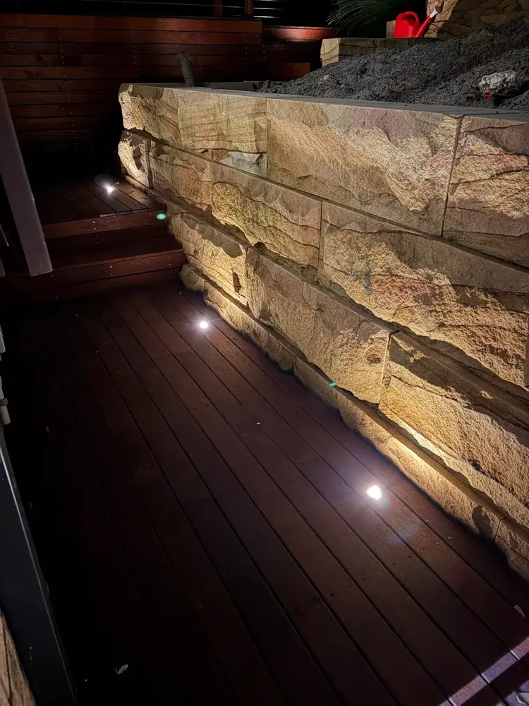 Sandstone block retaining wall beside lit timber steps at night in Blaxland