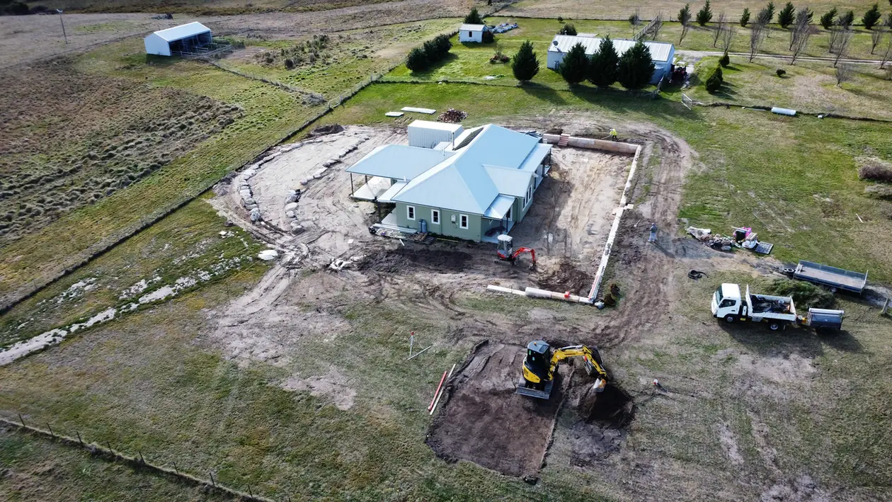 Drone view of excavation and sandstone log retaining walls around a rural house at Duckmaloi
