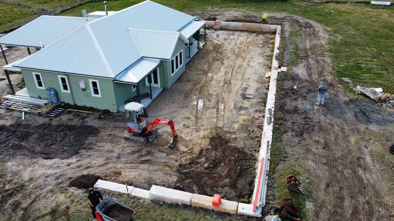 Sandstone log retaining wall and drainage trench beside a house at Duckmaloi near Oberon