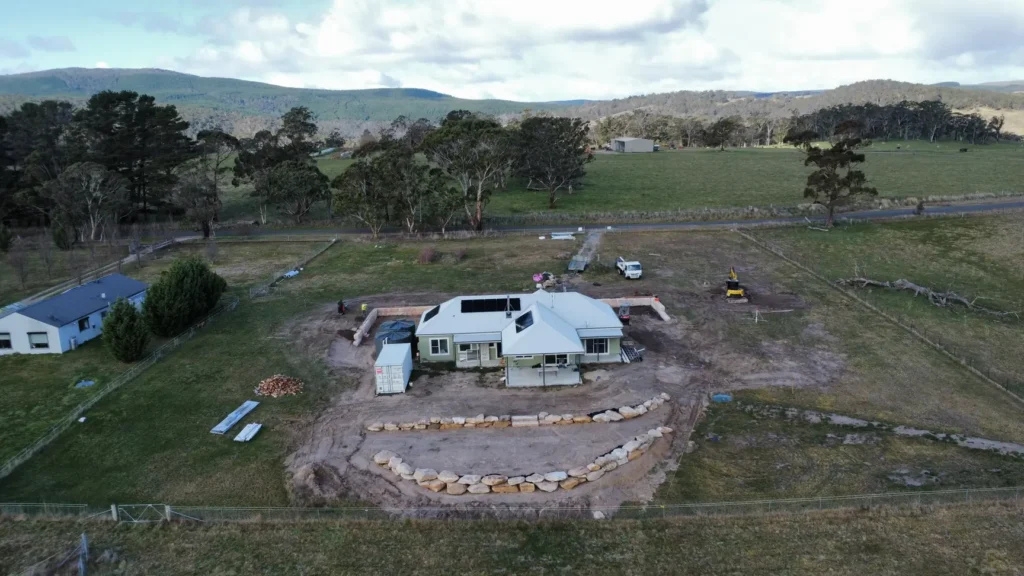Sandstone log and boulder retaining walls around a house on a rural block at Duckmaloi